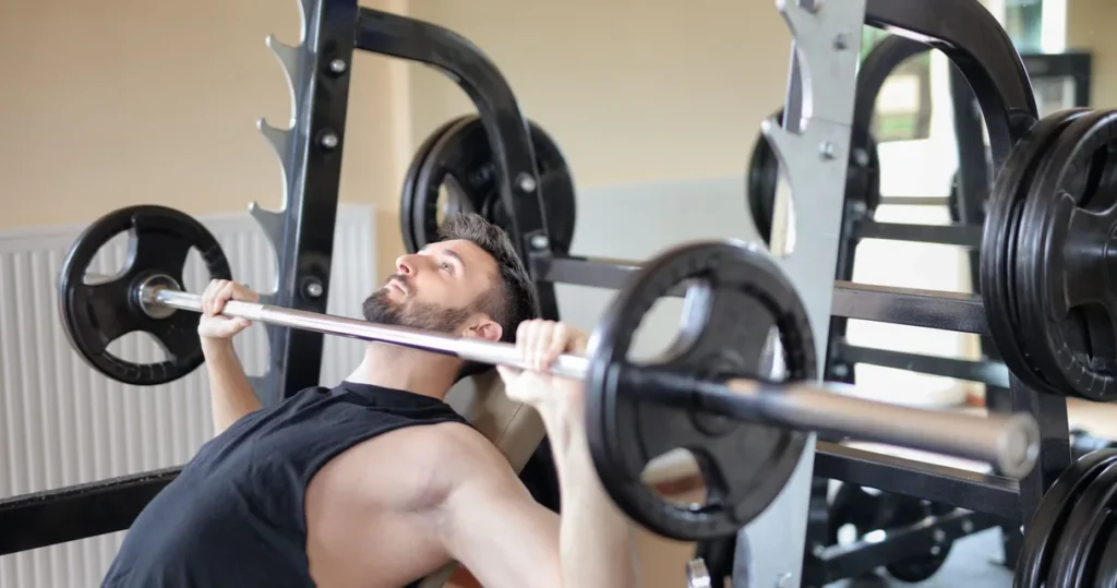Homem fazendo supino com barra na academia